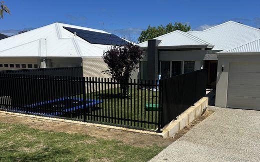 Black tubular front fencing beside a driveway and new home
