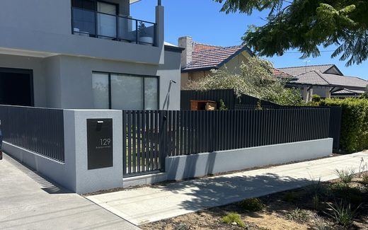 Black tubular fencing along the frontage of a modern rendered home