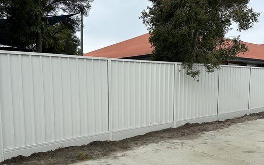Cream Colorbond fence running the length of a concrete driveway