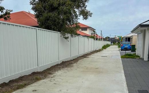 Long run of cream Colorbond fencing beside a residential driveway