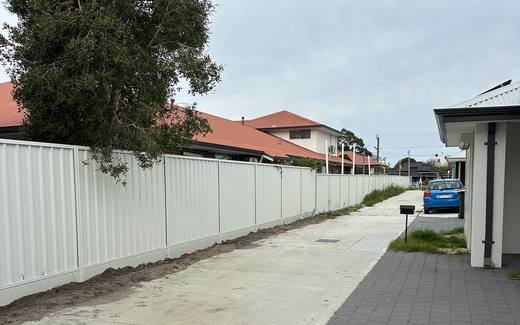 Long run of cream Colorbond fencing beside a paved side path