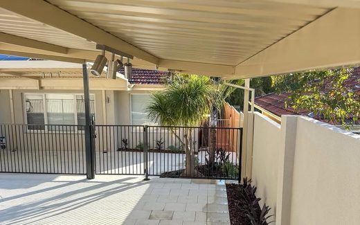 Cream Colorbond fence beside a paved alfresco area under a patio