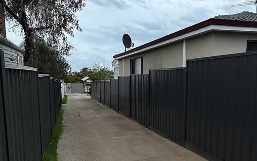 Dark Colorbond fence lining a driveway between two Perth homes