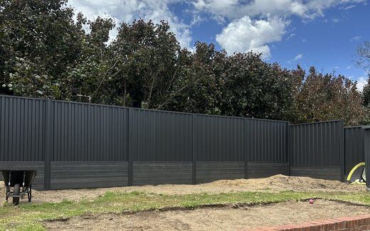 Dark Colorbond fence built above a brick retaining wall in a Perth backyard