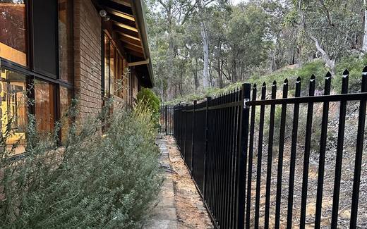 Black spear-top security fencing along a paved side path
