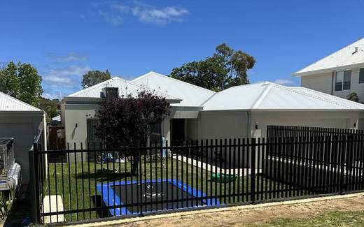 Black tubular pool fence running along a lawn behind a Perth home