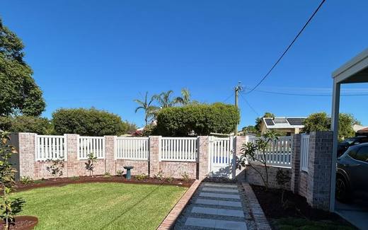 White picket fence and brick piers running along a paved front path