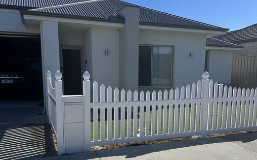 White PVC picket fence and matching gate across the frontage of a new home