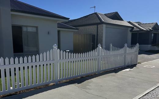White PVC picket fence along the front boundary of a newly built home