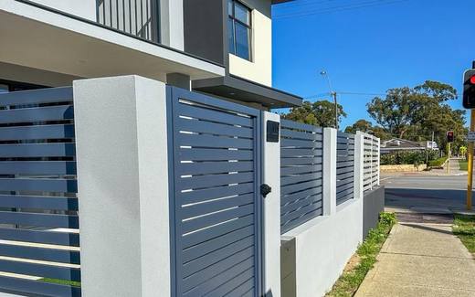Grey aluminium slat front fence with white rendered pillars at a two-storey home