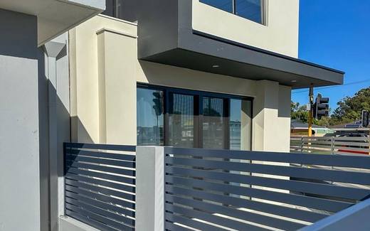 Aluminium slat fence panels and gate across a modern townhouse frontage
