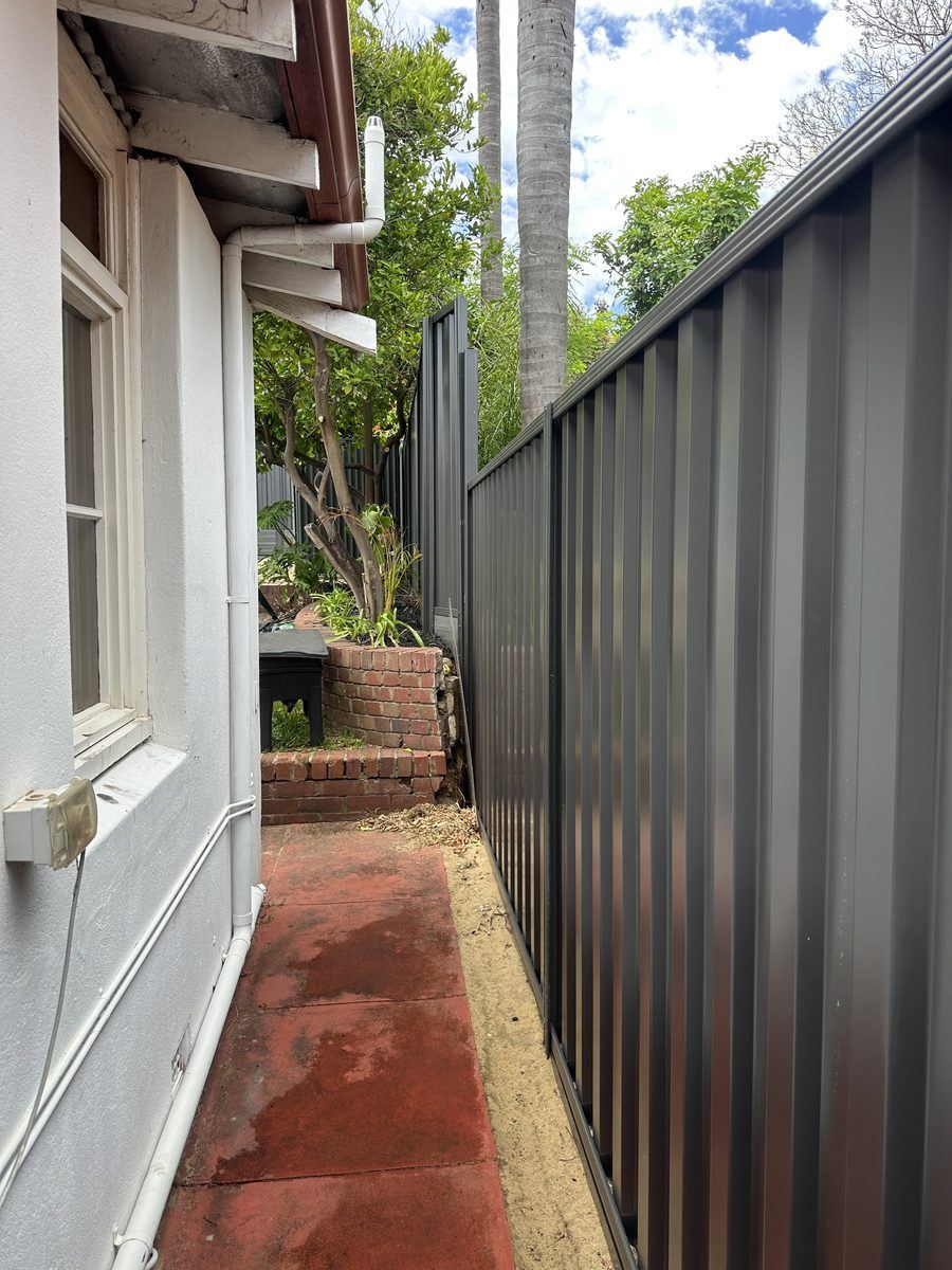 Colorbond fence running beside a narrow brick side path