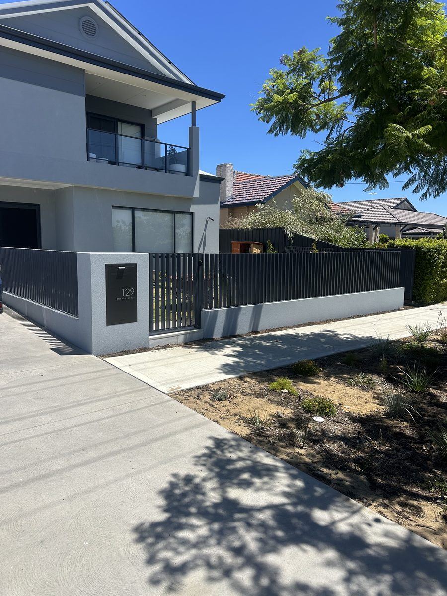 Black tubular fencing along the frontage of a modern rendered home