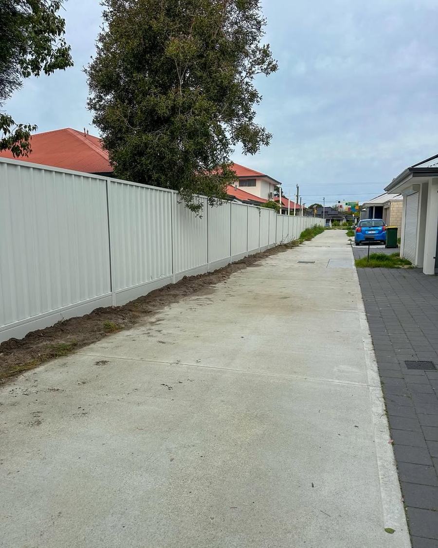 Long run of cream Colorbond fencing beside a residential driveway