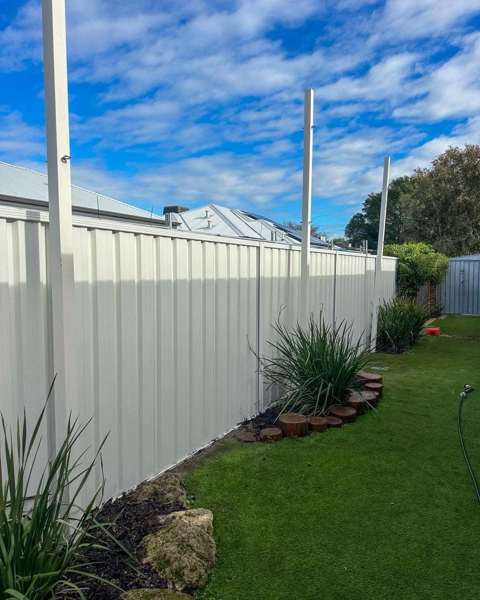 Cream Colorbond fence behind a planted garden bed and lawn