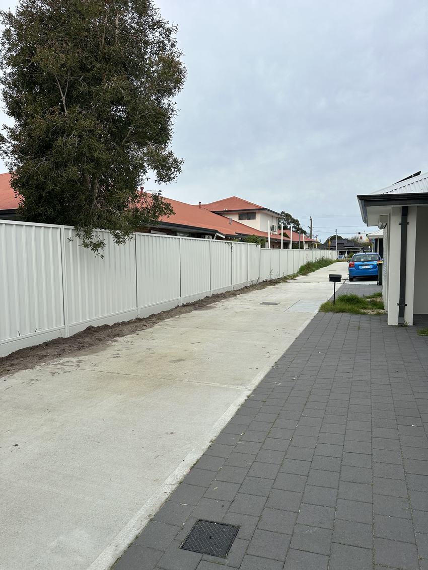 Long run of cream Colorbond fencing beside a paved side path