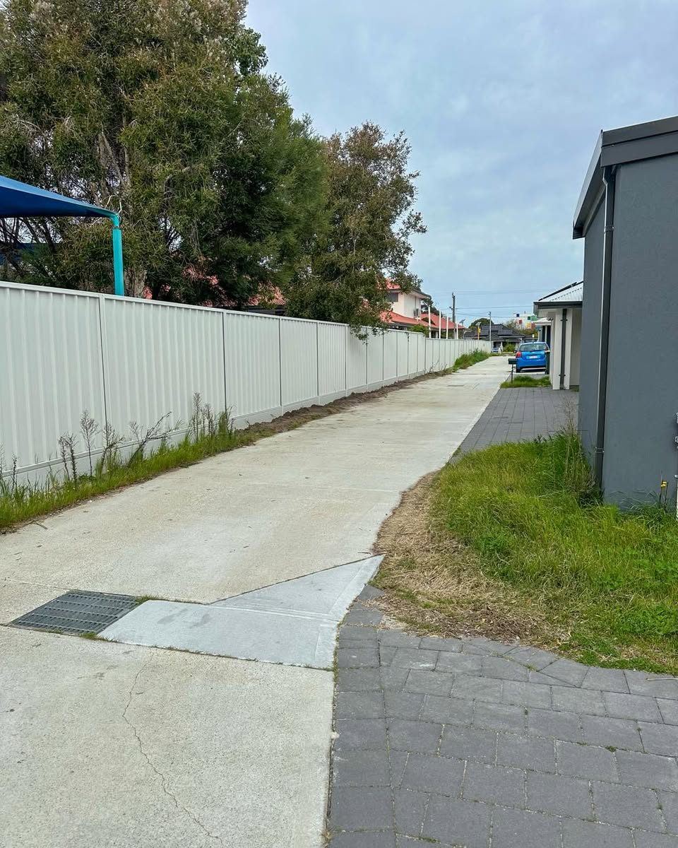 Cream Colorbond fence running beside a concrete pathway between homes