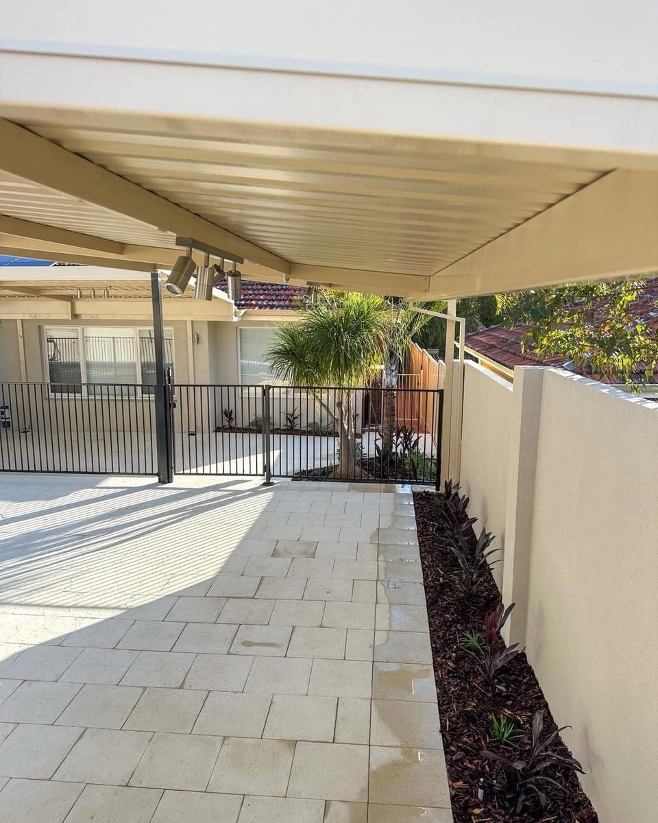 Cream Colorbond fence beside a paved alfresco area under a patio