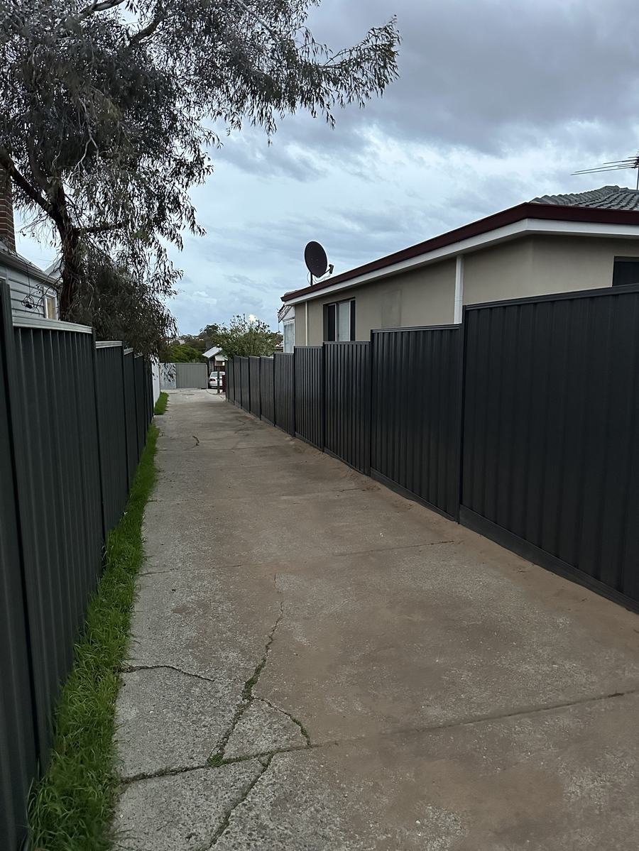 Dark Colorbond fence lining a driveway between two Perth homes