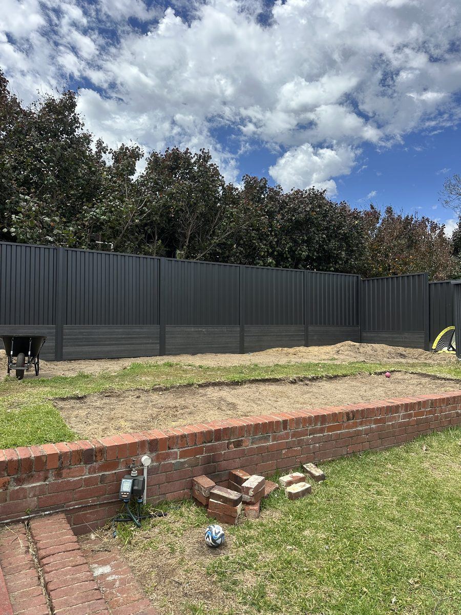 Dark Colorbond fence built above a brick retaining wall in a Perth backyard