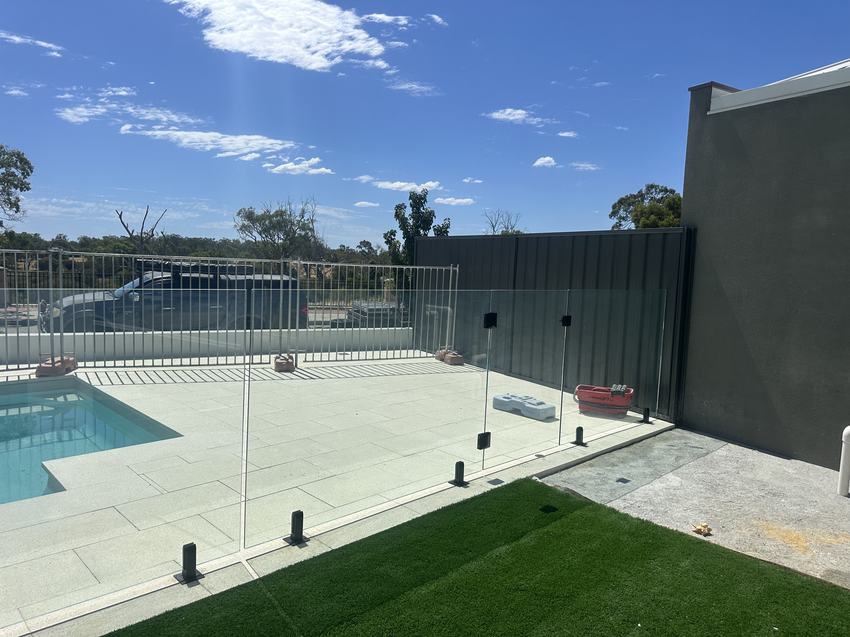 Frameless glass pool fence with a Colorbond boundary fence behind