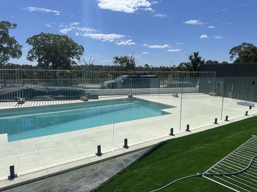 Frameless glass pool panels along the edge of a swimming pool