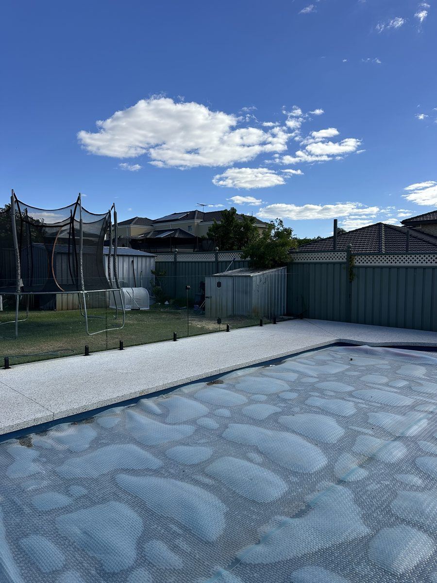 Frameless glass pool fencing separating a pool from a family backyard