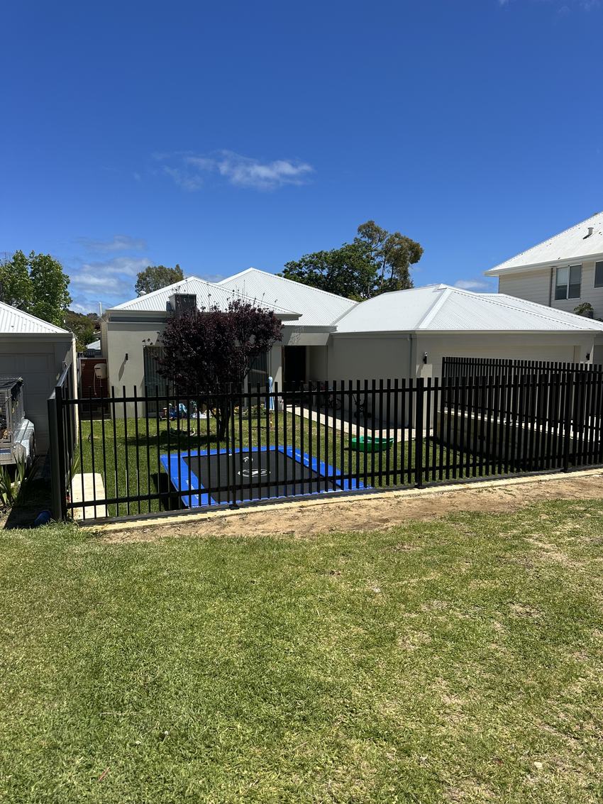 Black tubular pool fence running along a lawn behind a Perth home