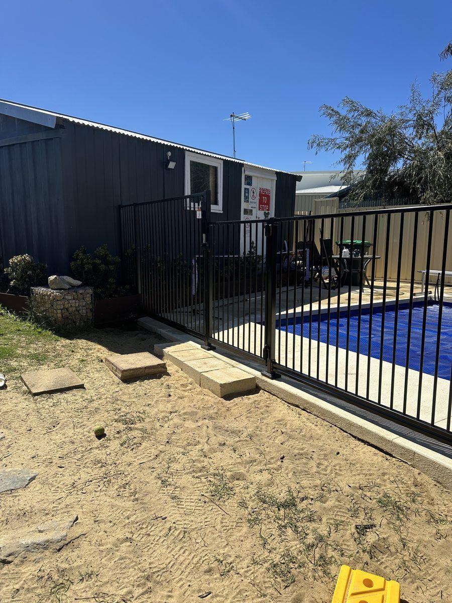 Black tubular pool fence along a limestone pool surround