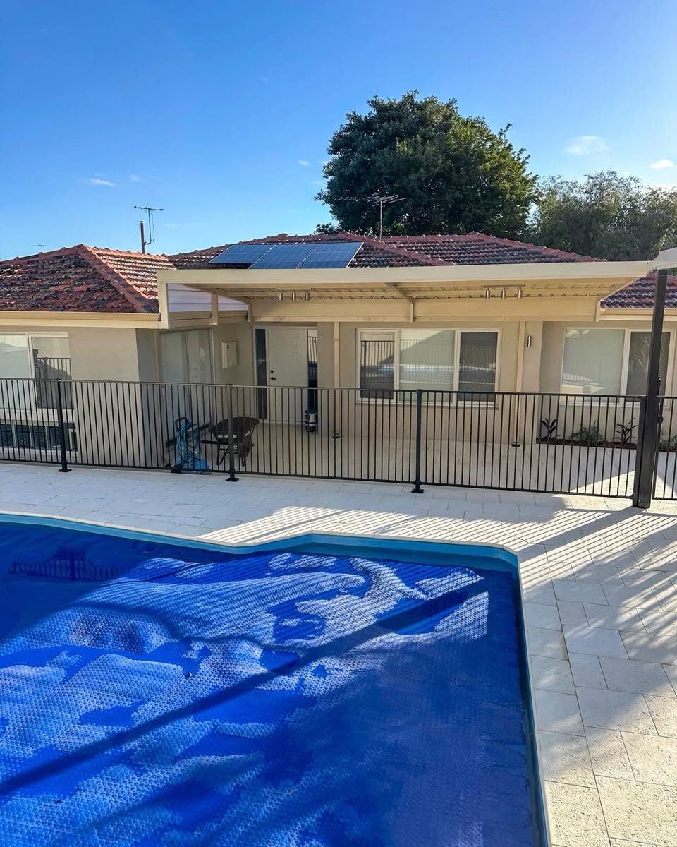 Black tubular pool fence beside a pool and alfresco area