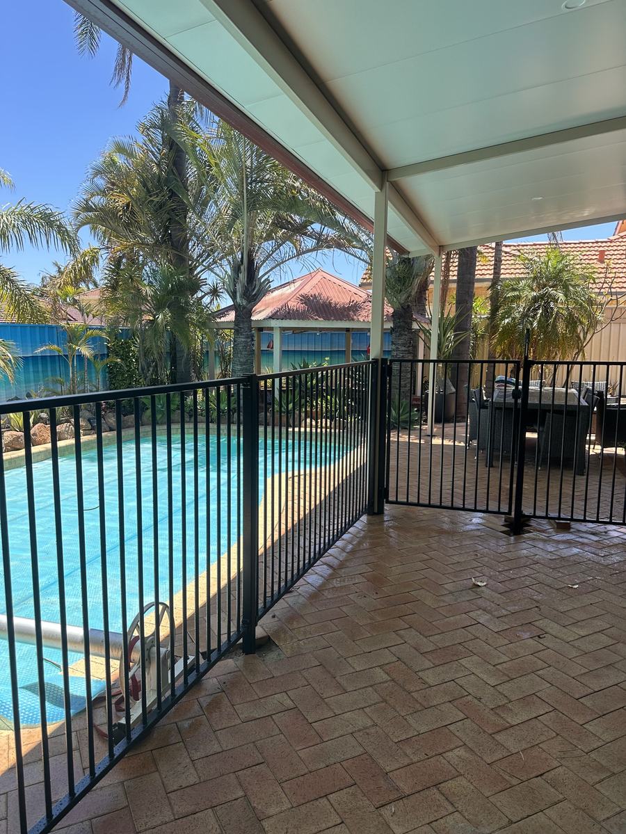 Black aluminium tubular pool fence around a paved pool and alfresco area