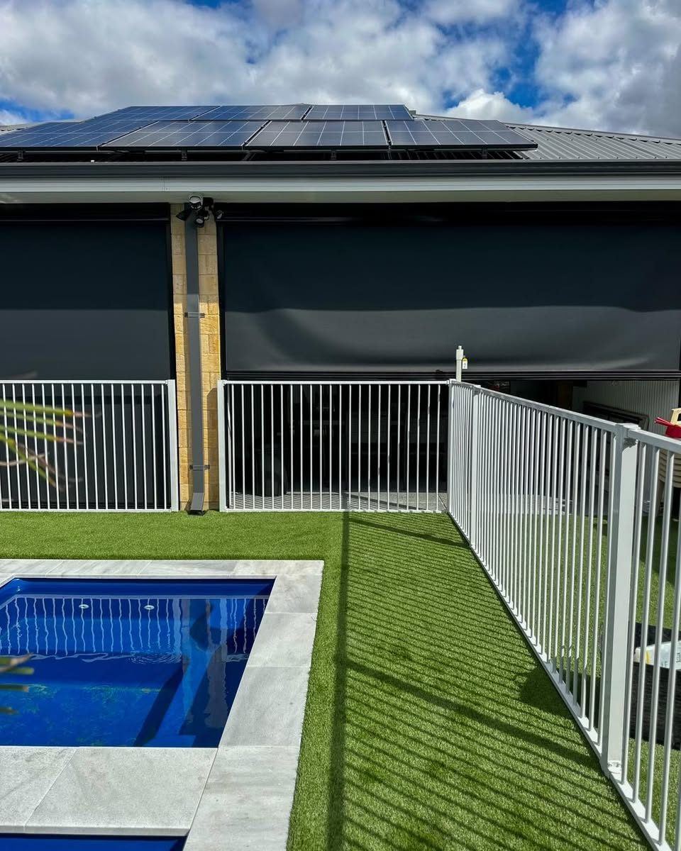 White tubular pool fence around a pool with artificial turf