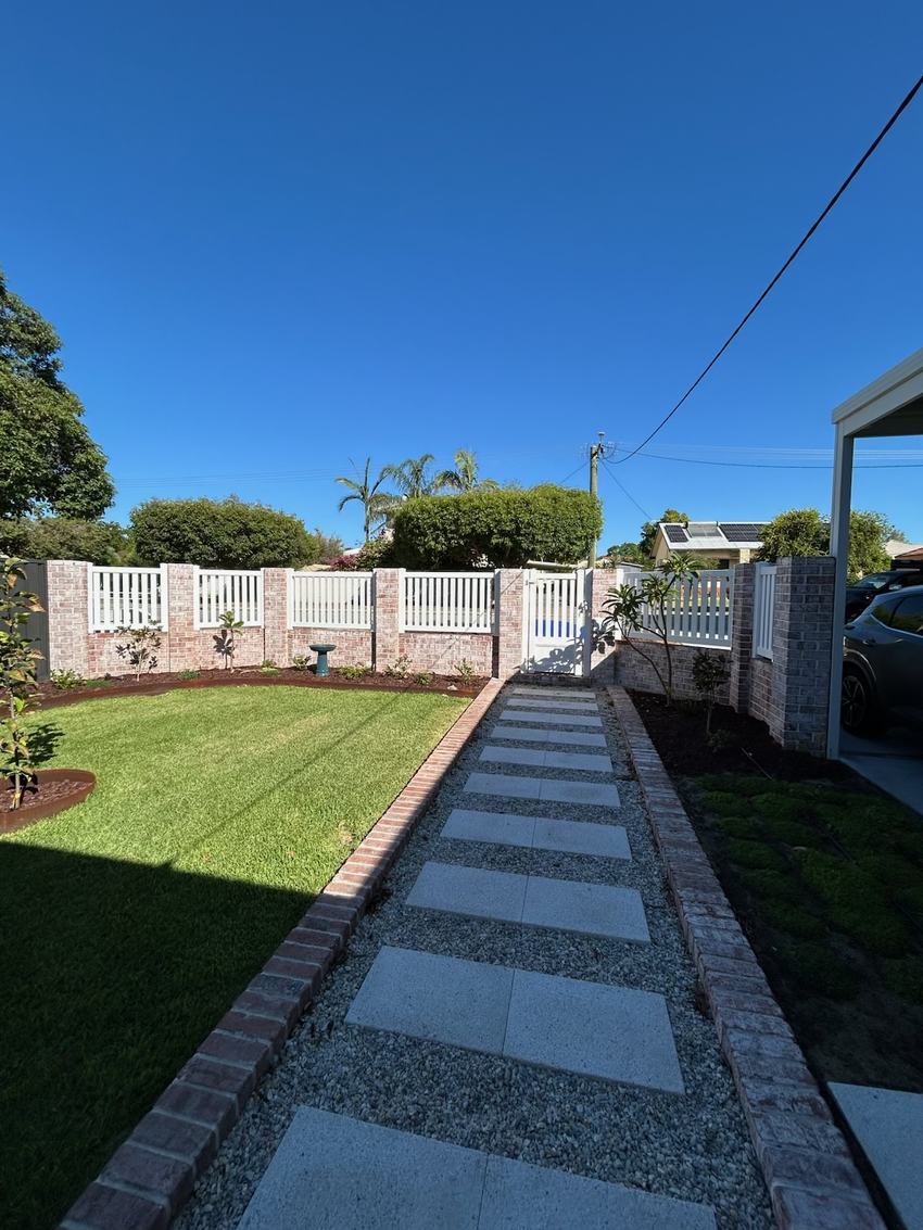 White picket fence and brick piers running along a paved front path