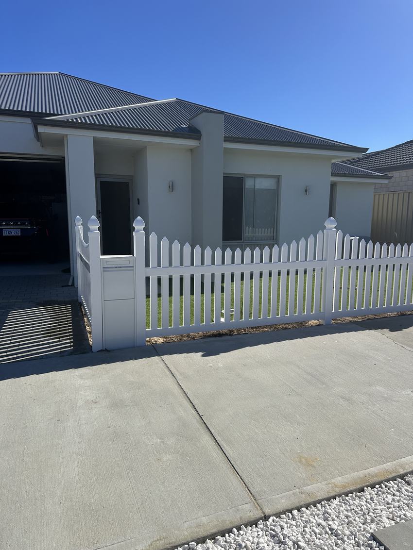 White PVC picket fence and matching gate across the frontage of a new home