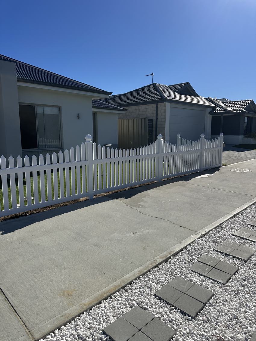 White PVC picket fence along the front boundary of a newly built home