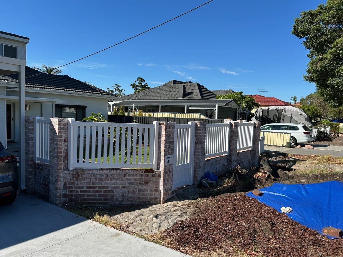 White PVC picket fence on brick piers across a suburban street frontage