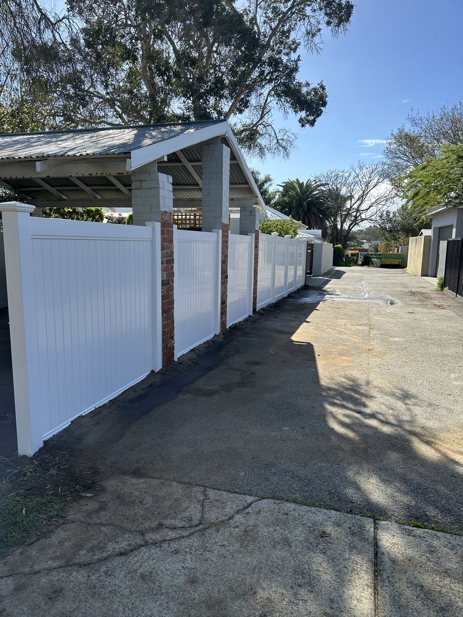 White PVC privacy fence running alongside a residential driveway