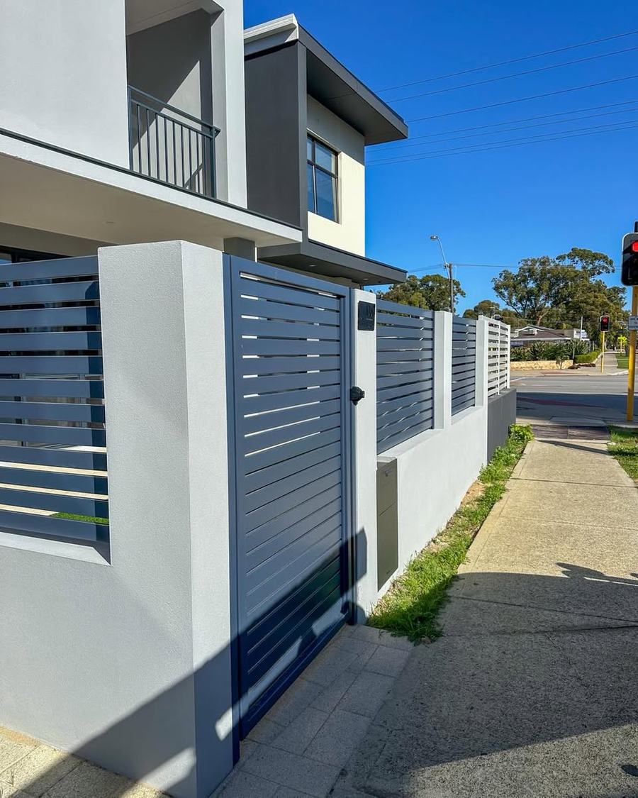Grey aluminium slat front fence with white rendered pillars at a two-storey home