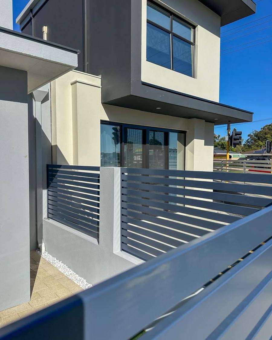 Aluminium slat fence panels and gate across a modern townhouse frontage