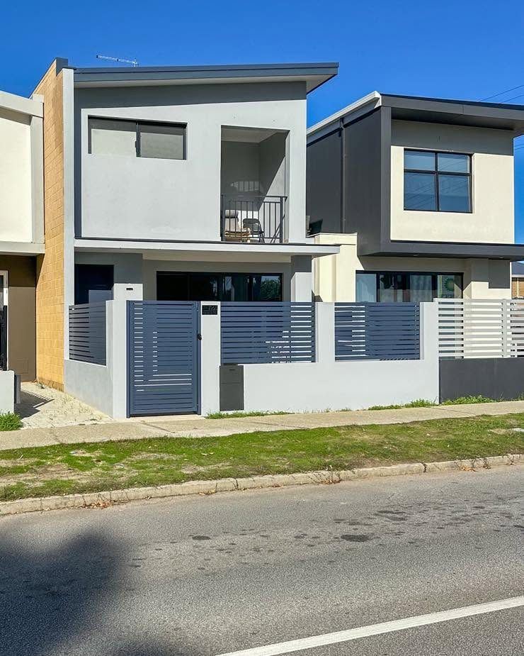 Grey aluminium slat fencing across a modern two-storey townhouse frontage